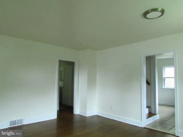 an empty room with wooden floor and mirror