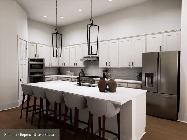 a kitchen with stainless steel appliances granite countertop a sink a stove a refrigerator and white cabinets with wooden floor