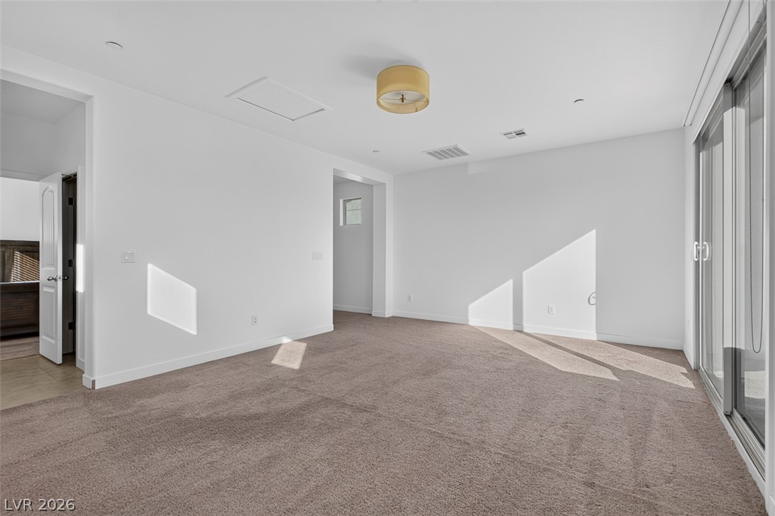 1100 East Sunset Road Henderson, NV 89011 - Photo 34 of 58 A spacious room offers comfortable carpeting, with natural light entering from the sliding glass door.