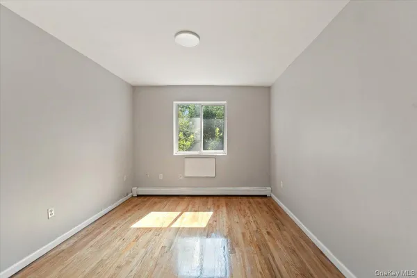an empty room with a window and wooden floor