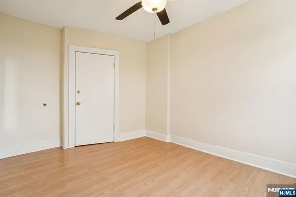 an empty room with a ceiling fan and wooden floor