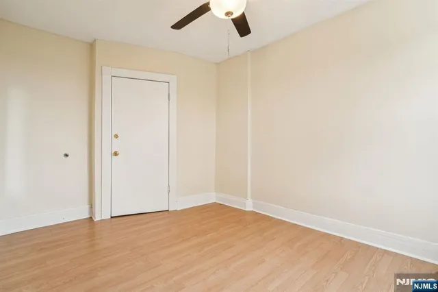 an empty room with a ceiling fan and wooden floor