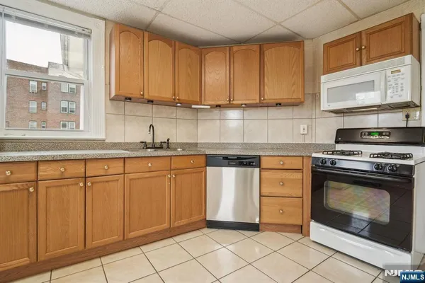a kitchen with granite countertop white cabinets stainless steel appliances a sink and a window