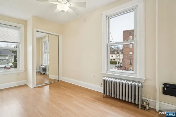 an empty room with wooden floor fan and windows