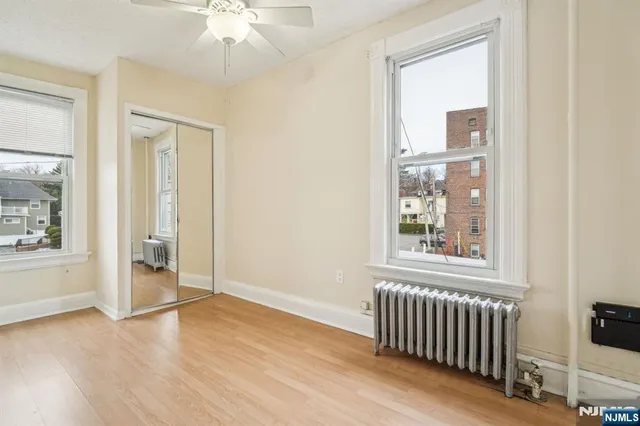 an empty room with wooden floor fan and windows