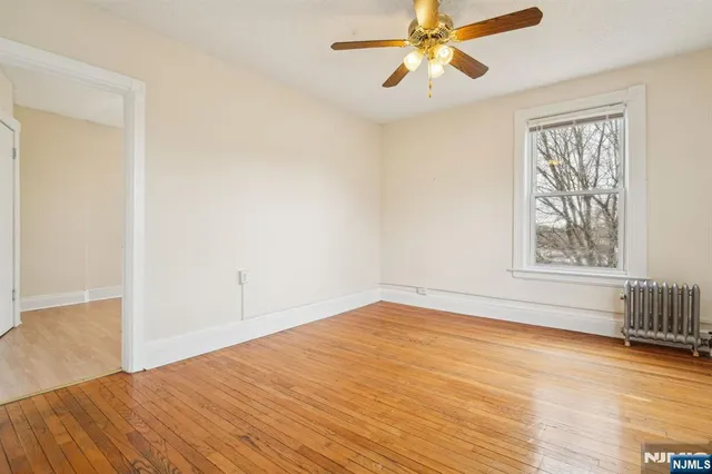 a view of empty room with wooden floor and fan