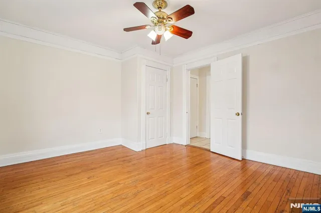 a view of a room with wooden floor and a ceiling fan