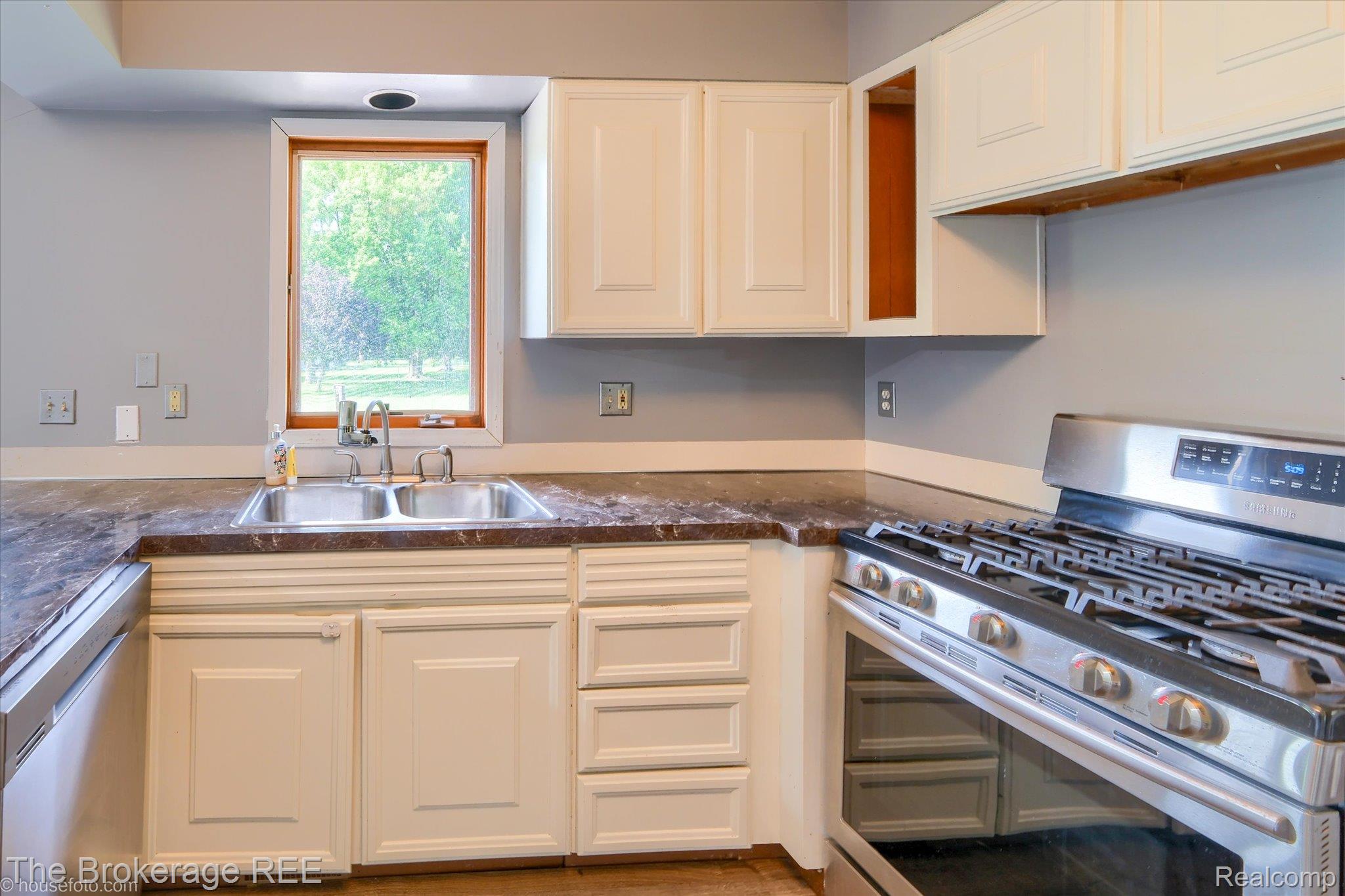 5495 East Coldwater Road Flint, MI 48506 - Photo 20 of 44 Kitchen featuring a stainless steel range, white cabinetry, a double basin sink, wood-trim window, and dark countertops