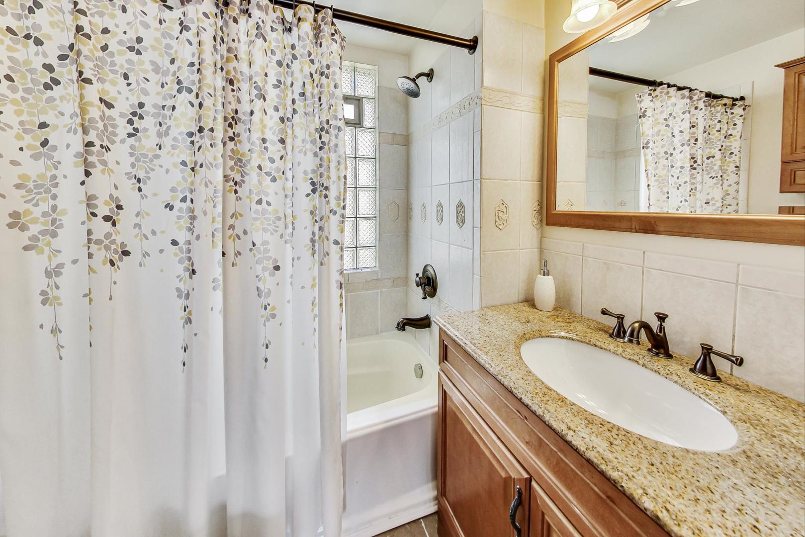 518 South Arlington Heights Road Arlington Heights, IL 60005 - Photo 18 of 42 a bathroom with a granite countertop sink a mirror a shower and a bathtub
