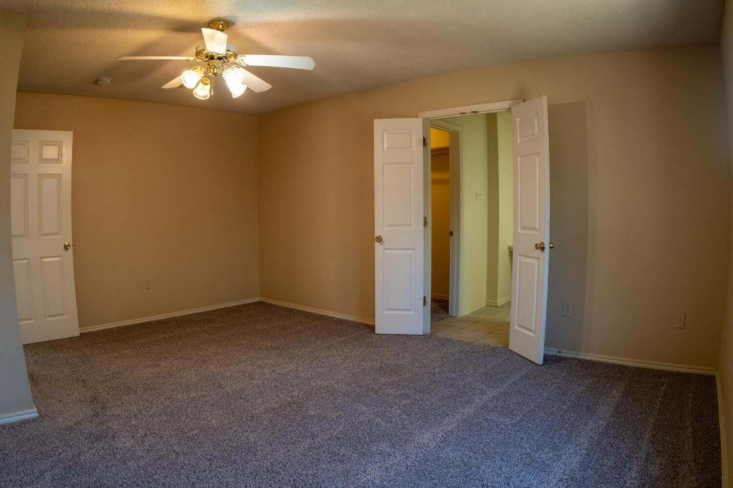 3409 97th Street Lubbock, TX 79423 - Photo 10 of 21 an empty room with a chandelier fan and windows