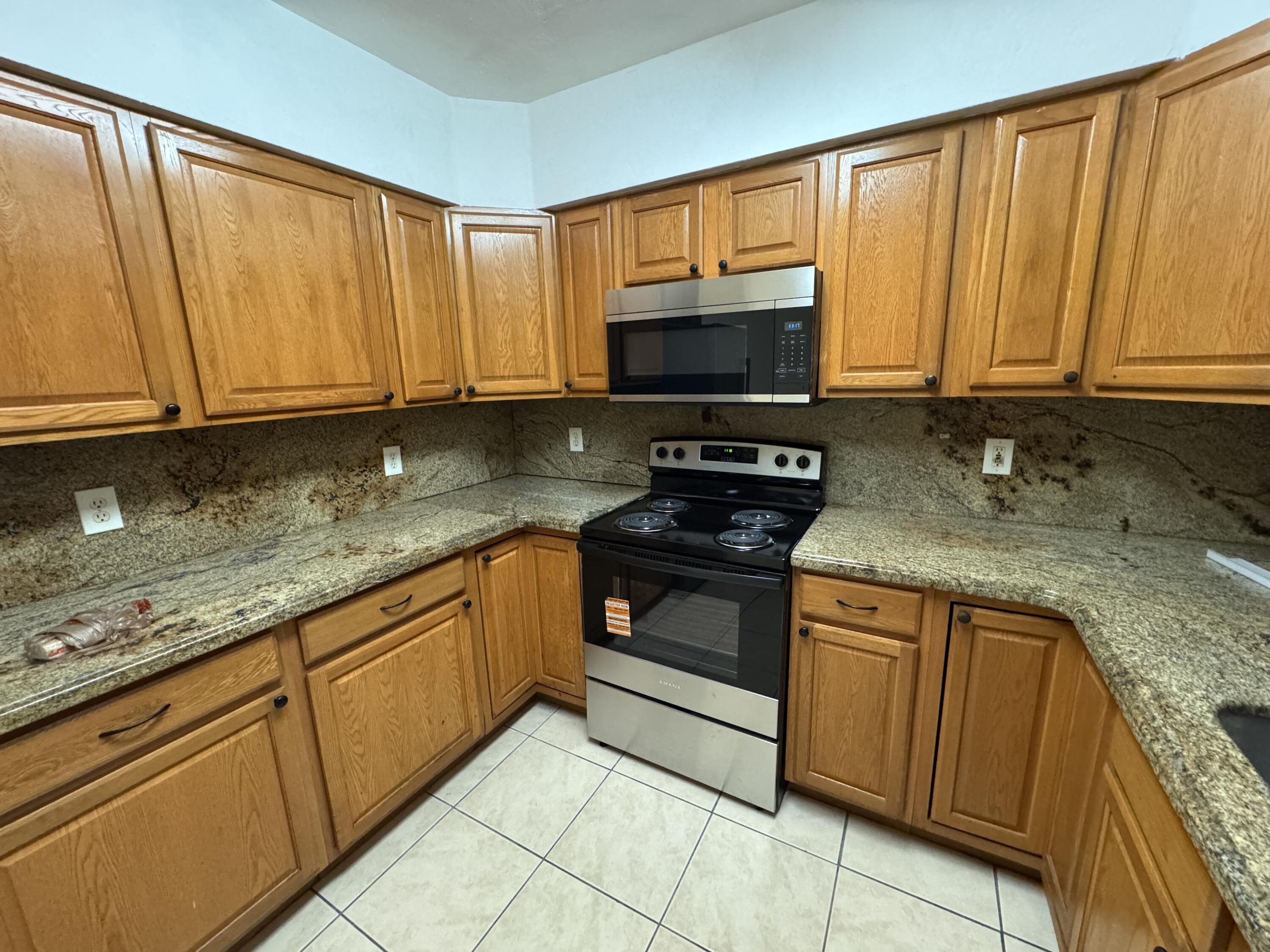 198 Southwest 15th Street Boca Raton, FL 33432 - Photo 3 of 11 a kitchen with granite countertop a sink stove and microwave