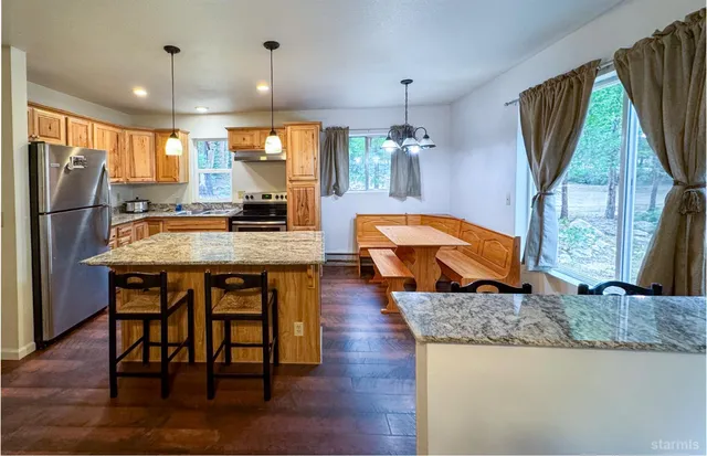 a kitchen with granite countertop a table chairs stove a refrigerator and kitchen island