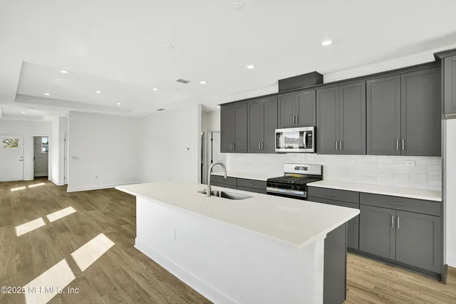 a kitchen with stainless steel appliances a sink a stove a refrigerator and cabinets