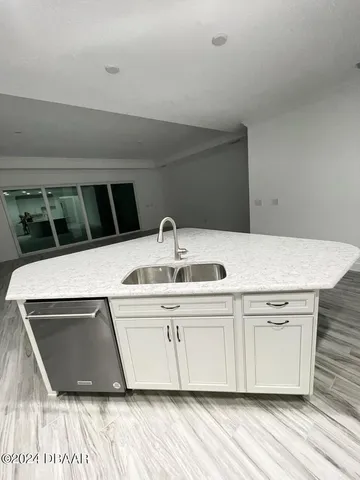 a room with kitchen island granite countertop a sink and cabinets
