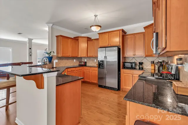 a kitchen with stainless steel appliances granite countertop a refrigerator a stove and a sink with cabinets