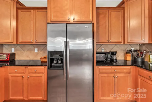 a kitchen with granite countertop a refrigerator and cabinets