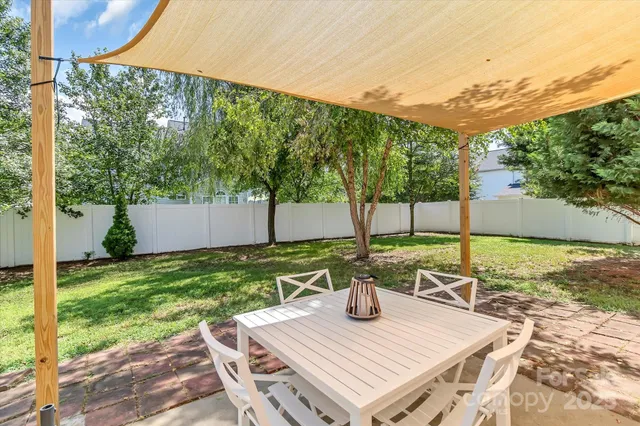 a view of a patio with table and chairs and potted plants with wooden fence