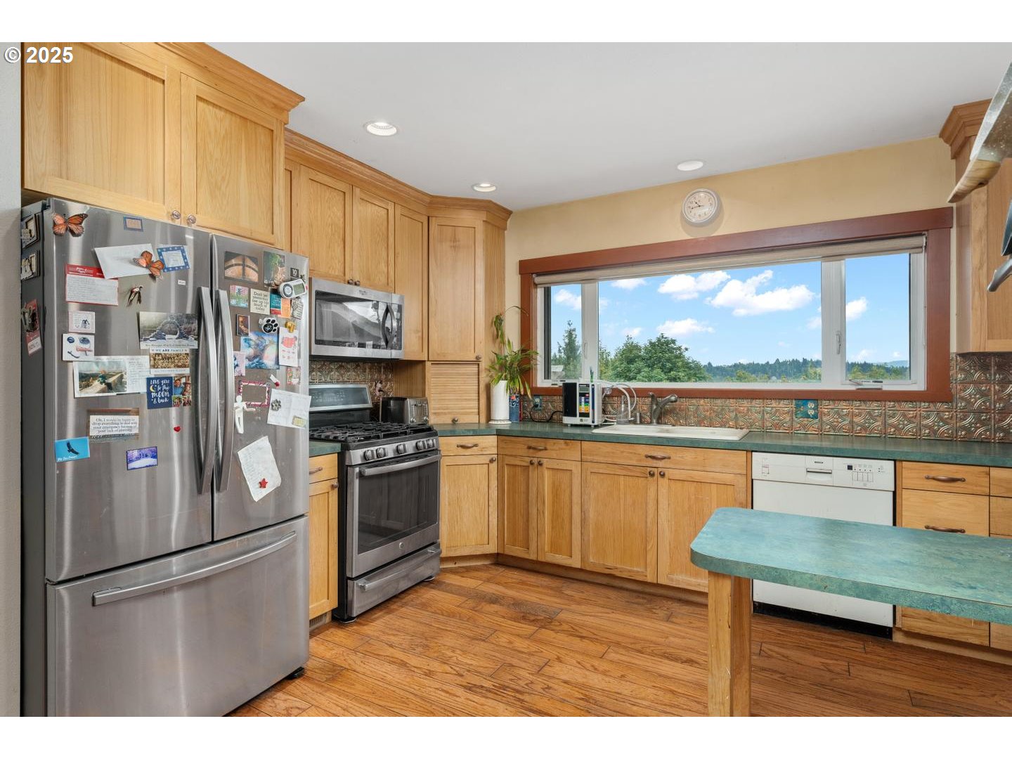 8970 Southeast Kingswood Way Damascus, OR 97089 - Photo 10 of 42 a kitchen with stainless steel appliances granite countertop a refrigerator a sink dishwasher a stove and a dining table with wooden floor