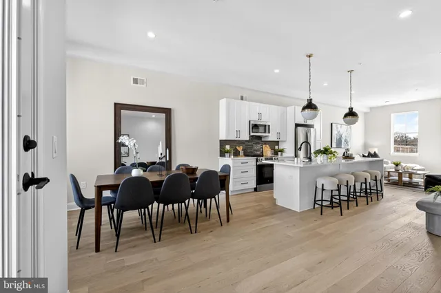 a view of a dining room and livingroom with furniture wooden floor a rug a painting and a chandelier