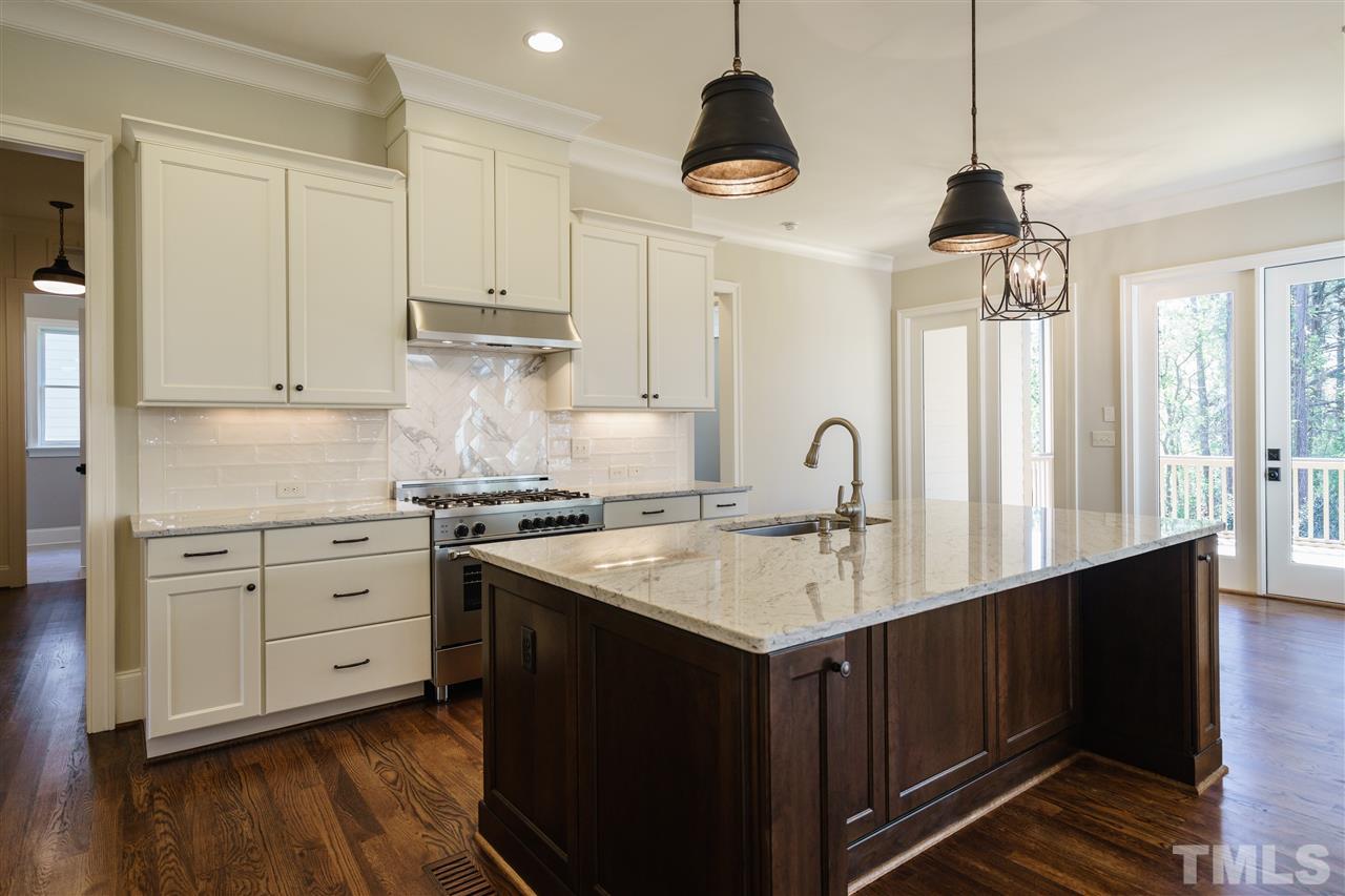 6120 Ponderosa Road Raleigh, NC 27612 - Photo 4 of 25 a kitchen with kitchen island granite countertop a stove a sink and white cabinets with wooden floor