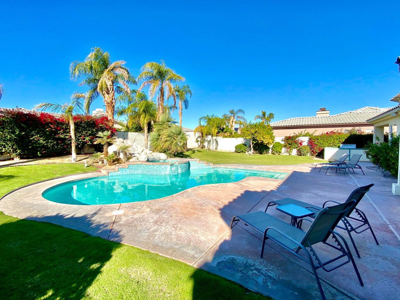 5 Victoria Falls Drive Rancho Mirage, CA 92270 - Photo 2 of 26 a view of a swimming pool with lawn chairs under an umbrella