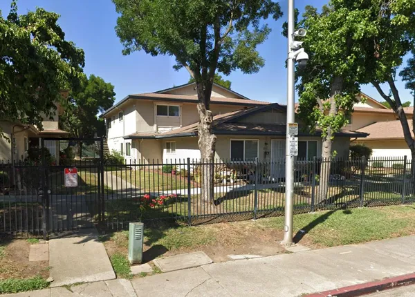 a front view of a house with a garden and tree
