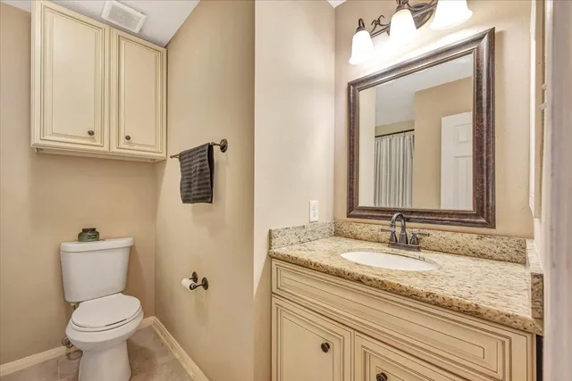 a bathroom with a granite countertop toilet sink and mirror