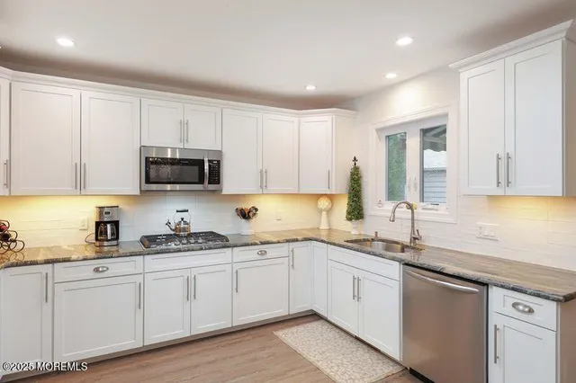 a kitchen with white cabinets appliances and a sink