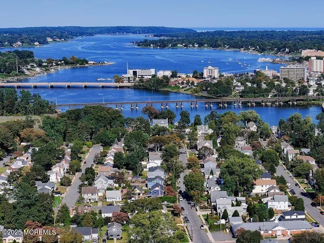 an aerial view of a city with lots of residential buildings ocean and mountain view in back