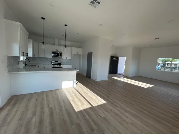 a kitchen with stainless steel appliances granite countertop a sink a stove a refrigerator a microwave oven with white cabinets and wooden floor