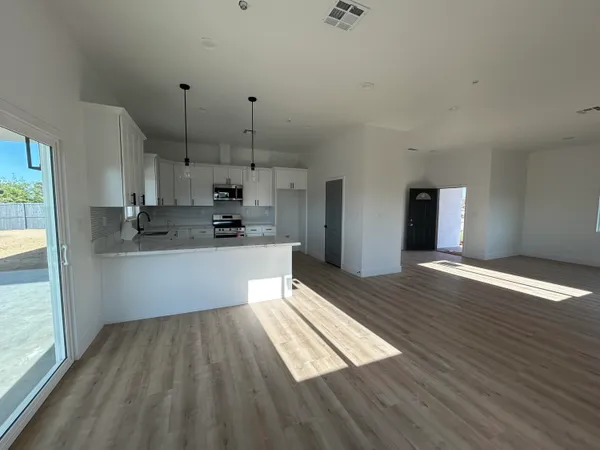 a kitchen with stainless steel appliances granite countertop a refrigerator a sink dishwasher a stove and white countertops with wooden floor