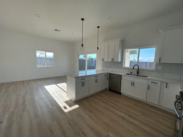a large kitchen with granite countertop a large window a sink stainless steel appliances and cabinets