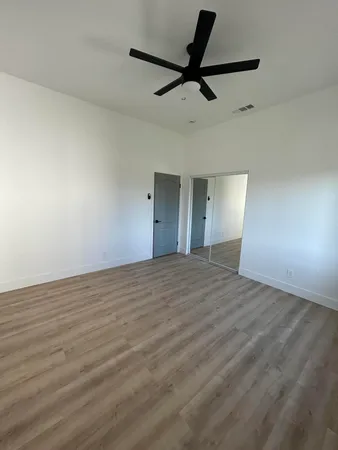 a view of empty room with wooden floor and fan