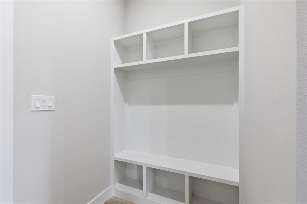 713 Anne Road Van Alstyne, TX 75495 - Photo 24 of 29 Built-in white shelving unit with varied cubby sizes, a broad central shelf, and lower compartments