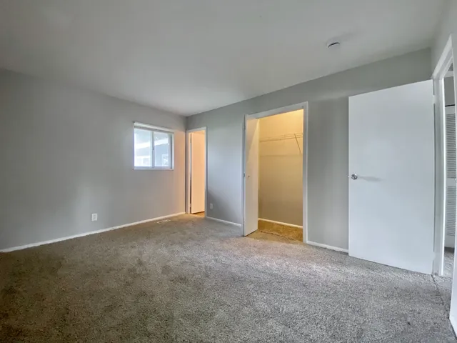 a view of an empty room with window and closet area