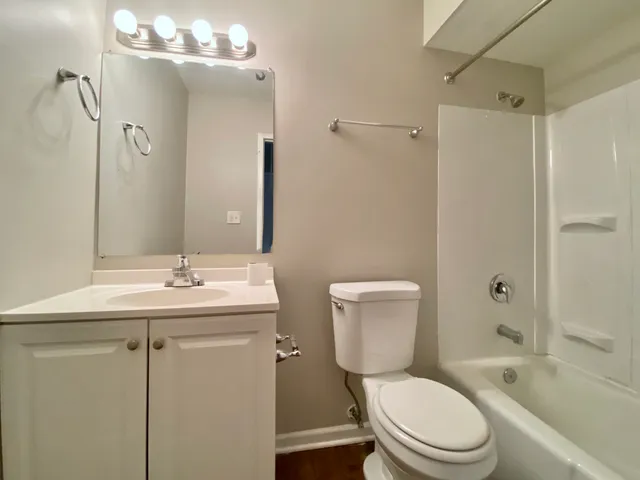 a bathroom with a toilet a sink a mirror a bathtub and shower