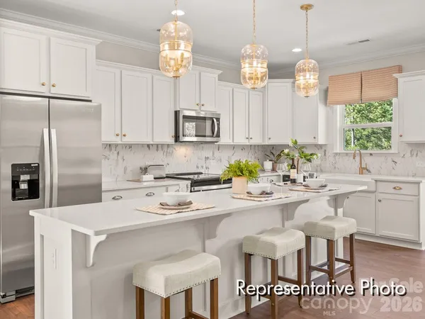a kitchen with stainless steel appliances kitchen island granite countertop a table chairs sink and cabinets