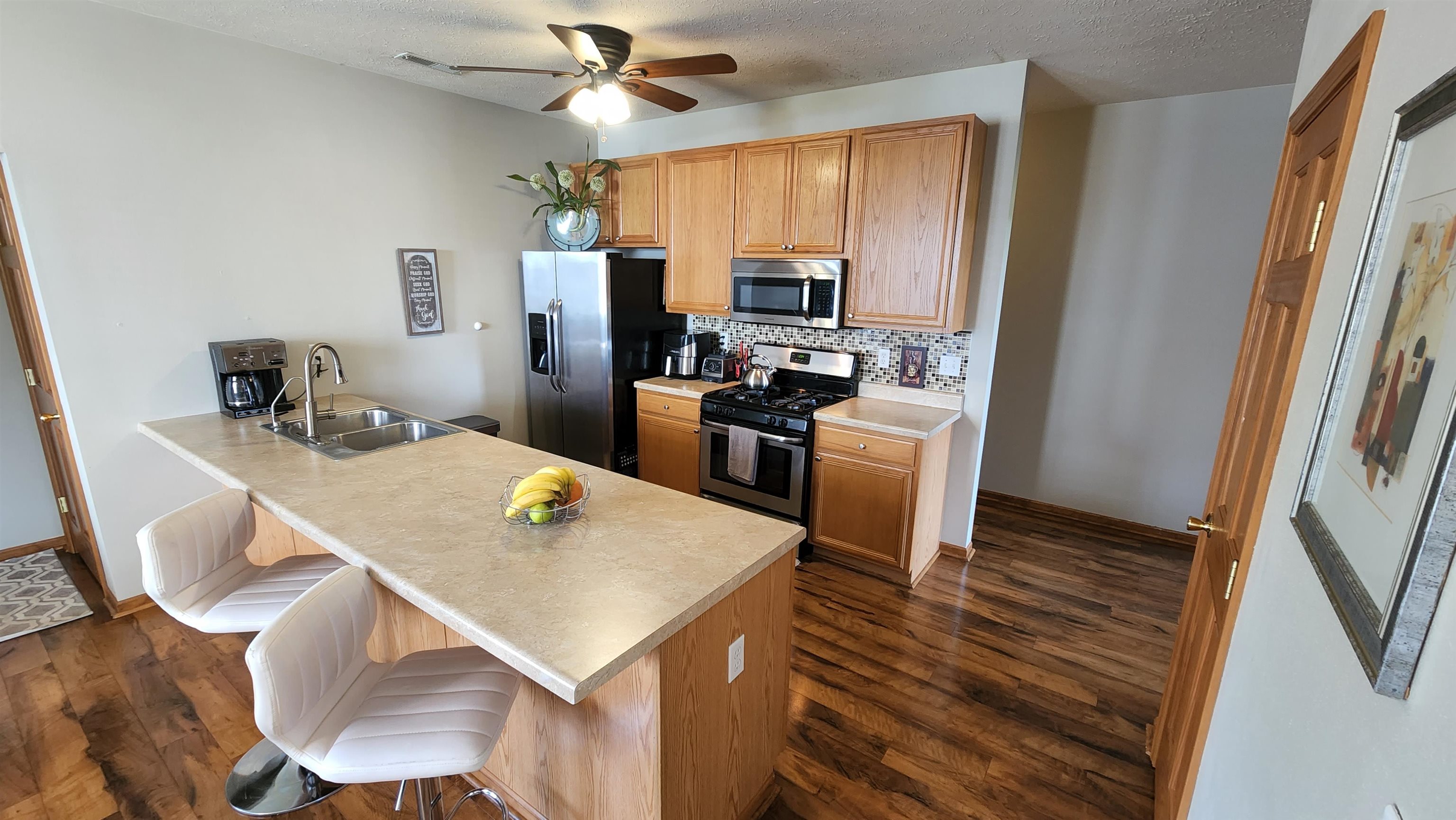 10326 Marblewing Road Roscoe, IL 61073 - Photo 5 of 12 a kitchen with stainless steel appliances a stove a refrigerator a sink a dining table and chairs with wooden floor