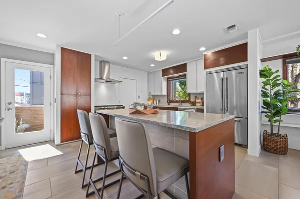 a kitchen with granite countertop a refrigerator a sink a dining table and chairs