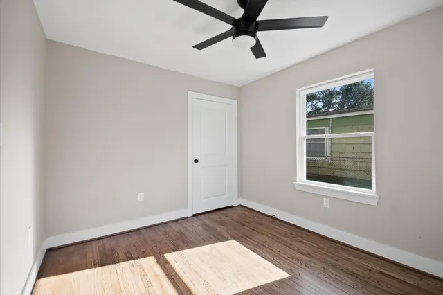 a view of an empty room with a window and wooden floor