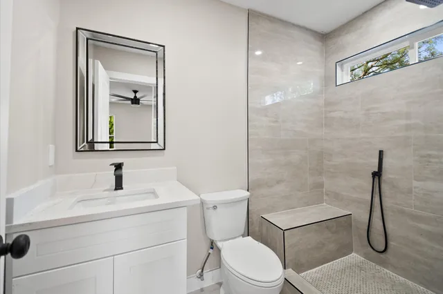 a bathroom with a toilet sink vanity shower and mirror