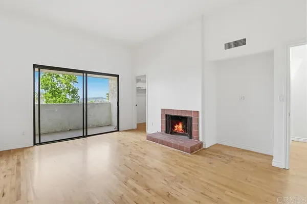 a view of empty room with wooden floor and fireplace