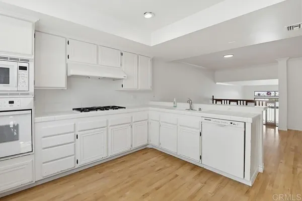 a kitchen with granite countertop white cabinets and white appliances