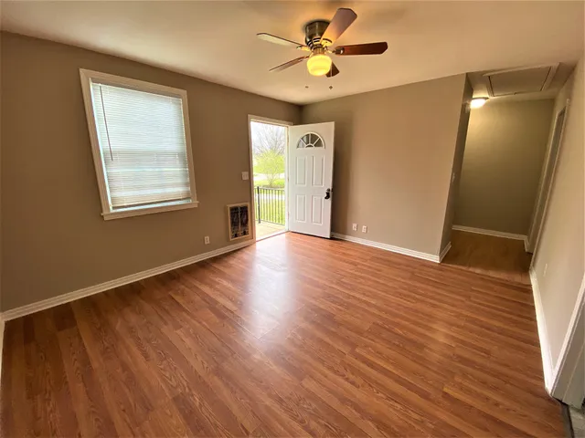 a view of an empty room with wooden floor and a window