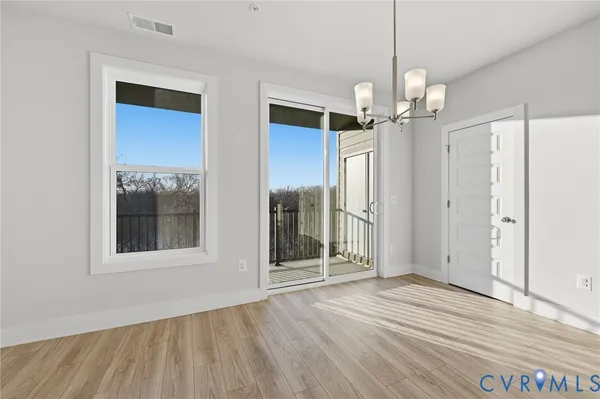 a view of a room with wooden floor chandelier and windows