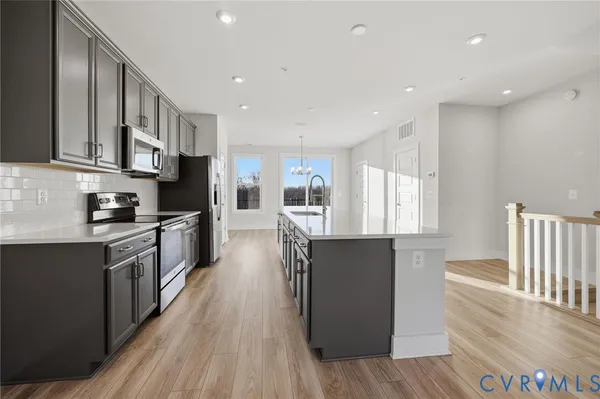 a large kitchen with stainless steel appliances granite countertop a lot of counter space and wooden floors