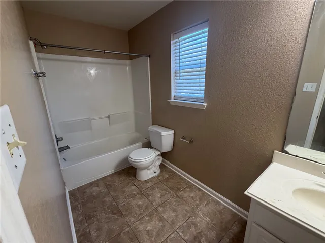 an empty room with a chandelier fan and windows