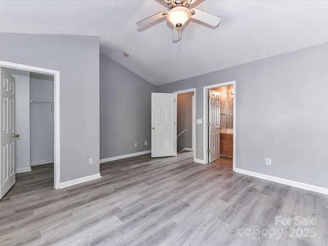 an empty room with wooden floor chandelier fan and windows