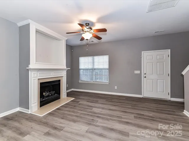 a view of a livingroom with a fireplace a ceiling fan and wooden floor