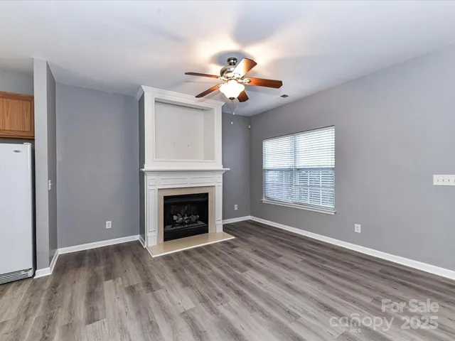 a view of an empty room with chandelier fan and a fireplace